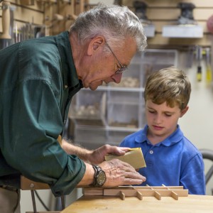 Bob shows his grandson sanding techniques for a box insert.